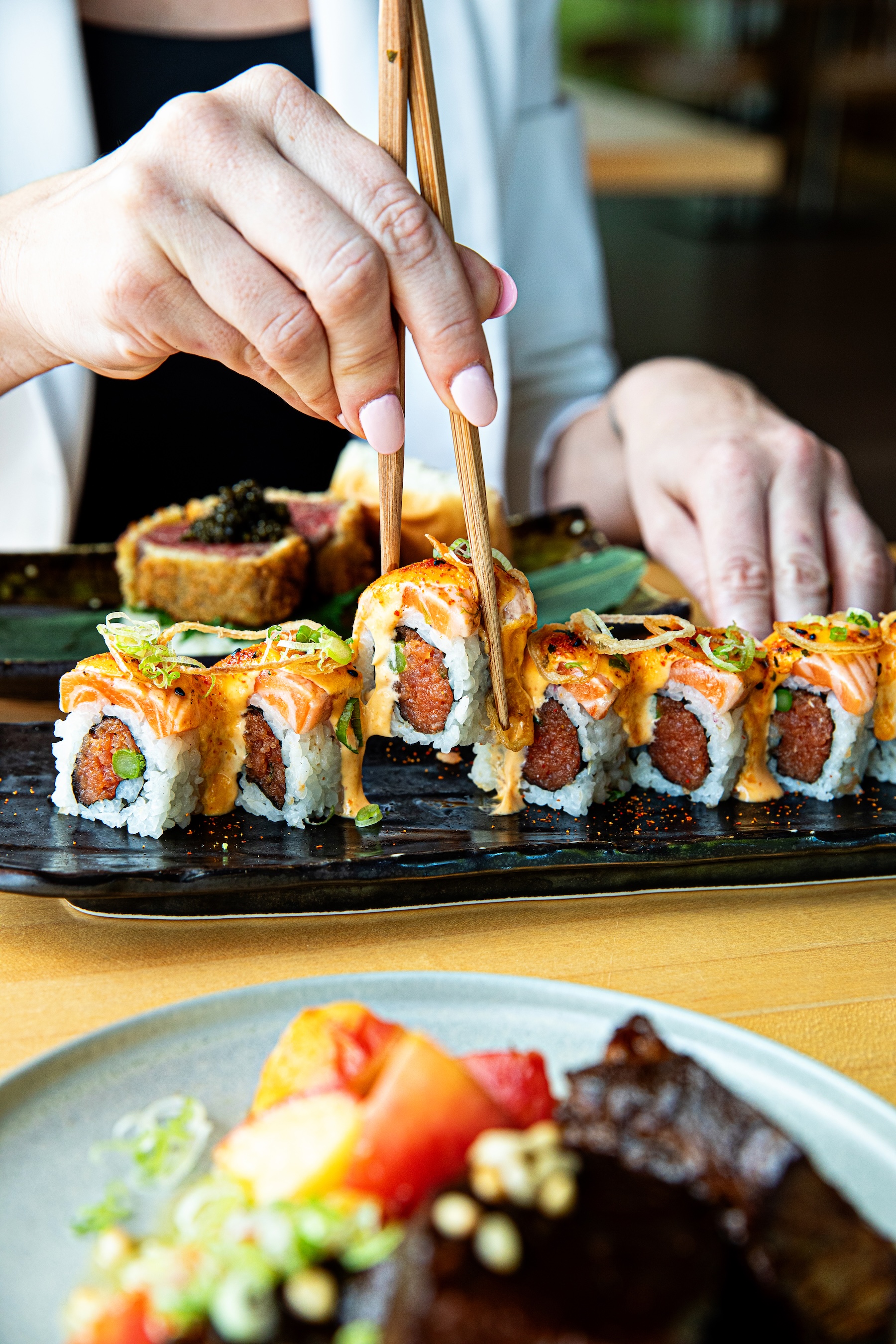 a person holding chopsticks to a sushi roll