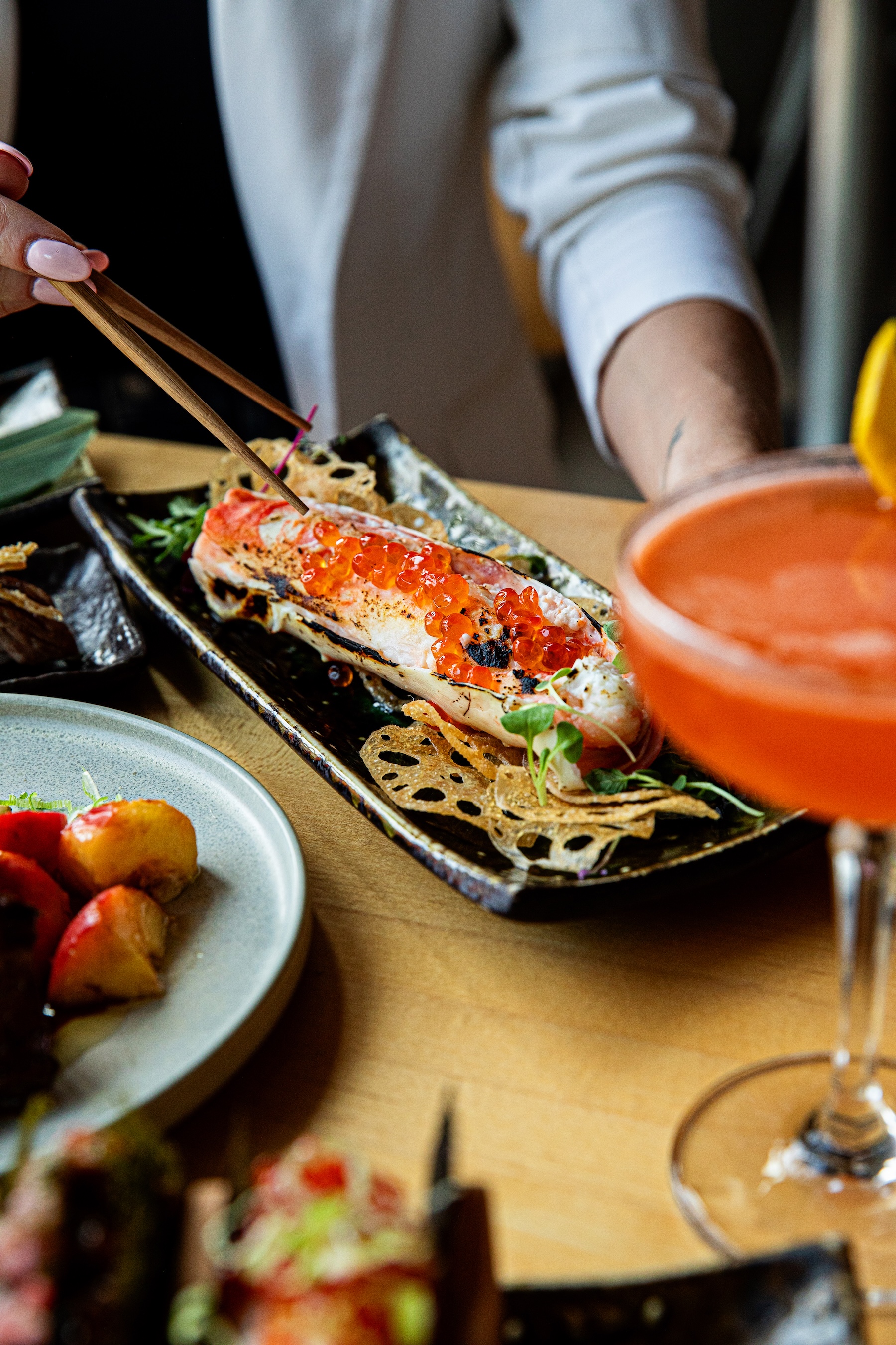 a person holding chopsticks to a plate of food