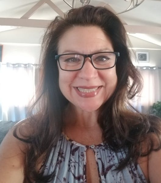 a woman wearing glasses and smiling at the camera