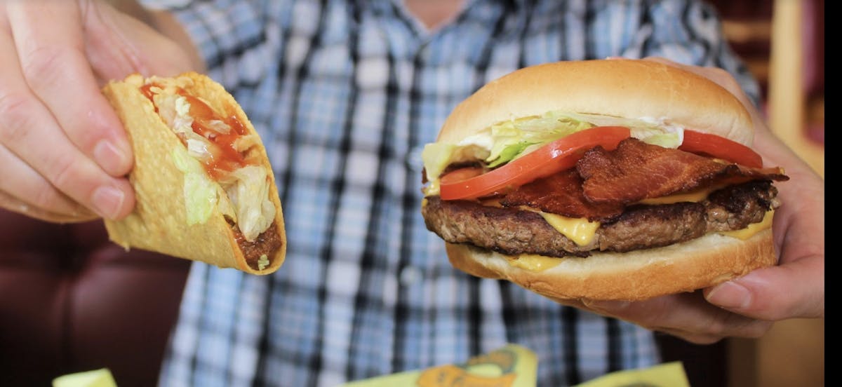 a hand holding a hot dog on a bun
