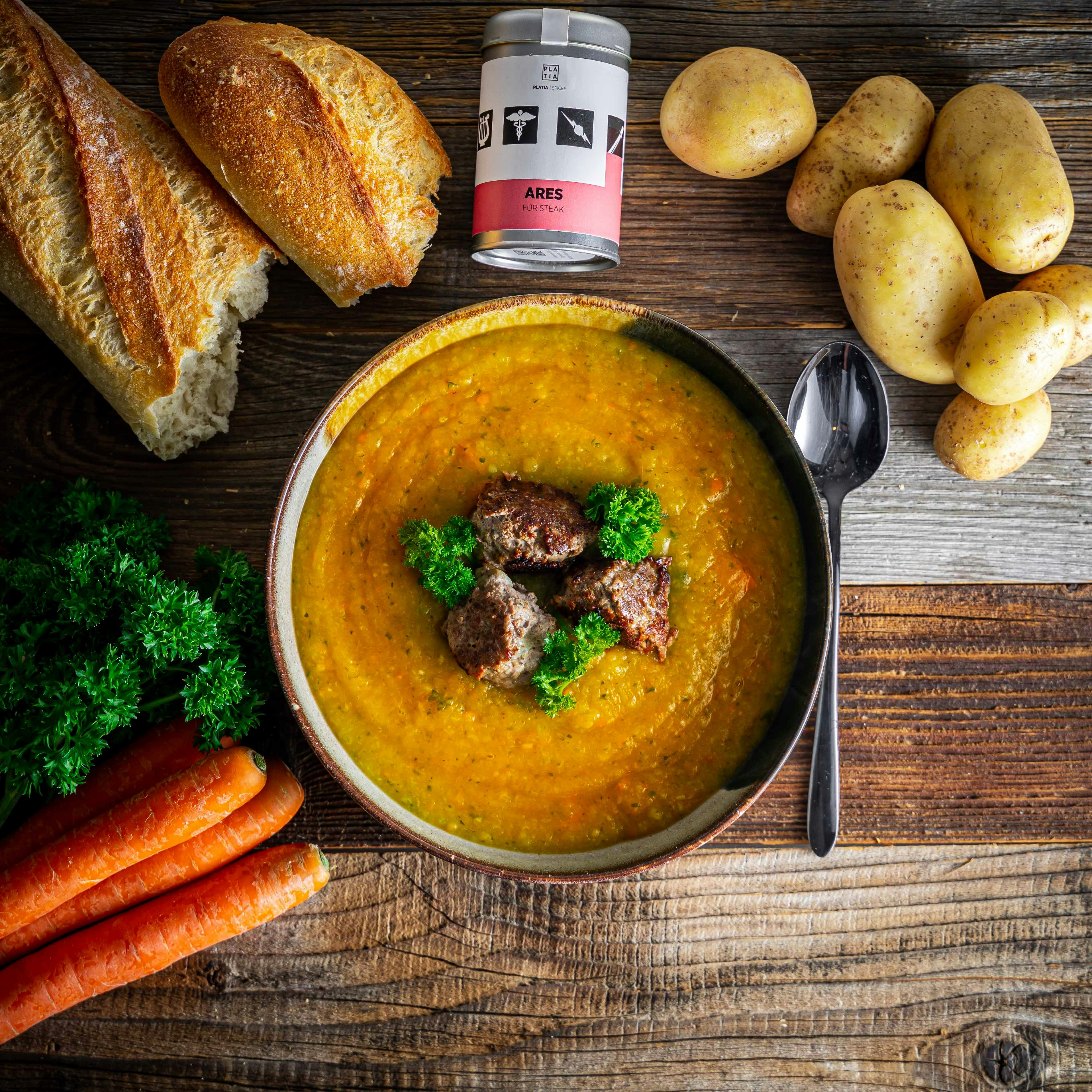 a bowl of soup next to a bread and vegetables