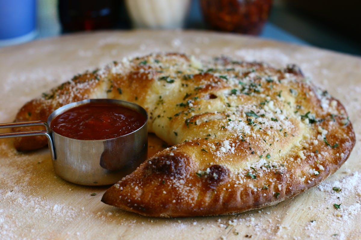 a Calzone next to a sauce