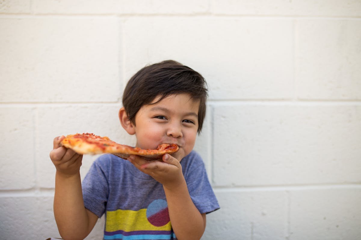 a young boy eating a slice of pizza