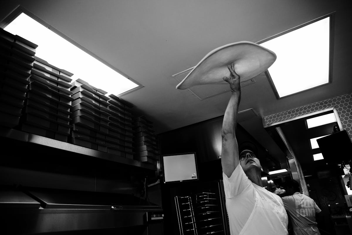 a man throwing a pizza dough in the air