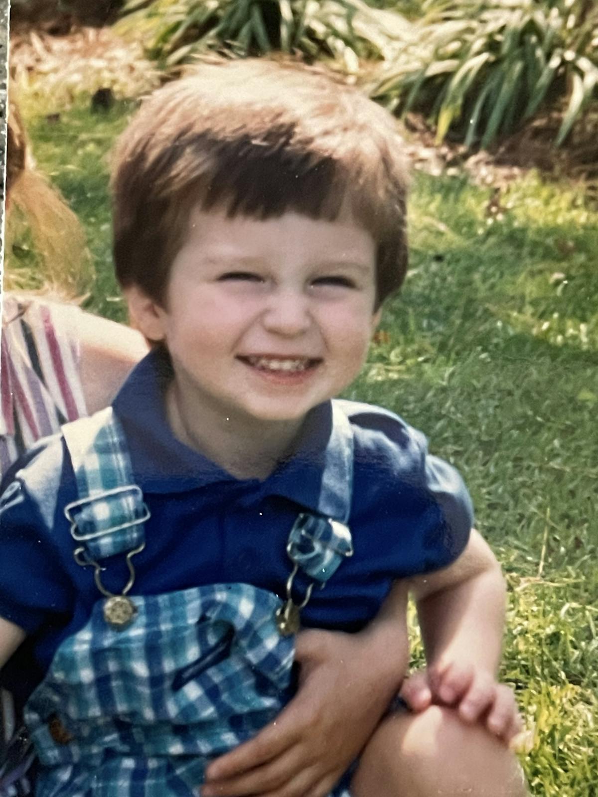 a little boy that is sitting in the grass