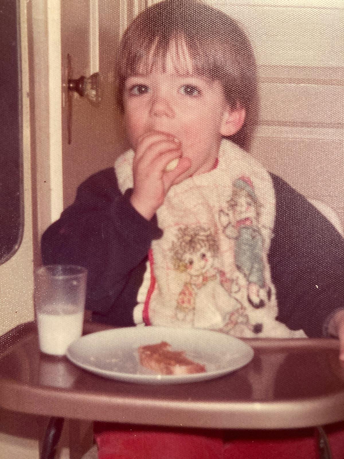 a young boy sitting at a table eating food