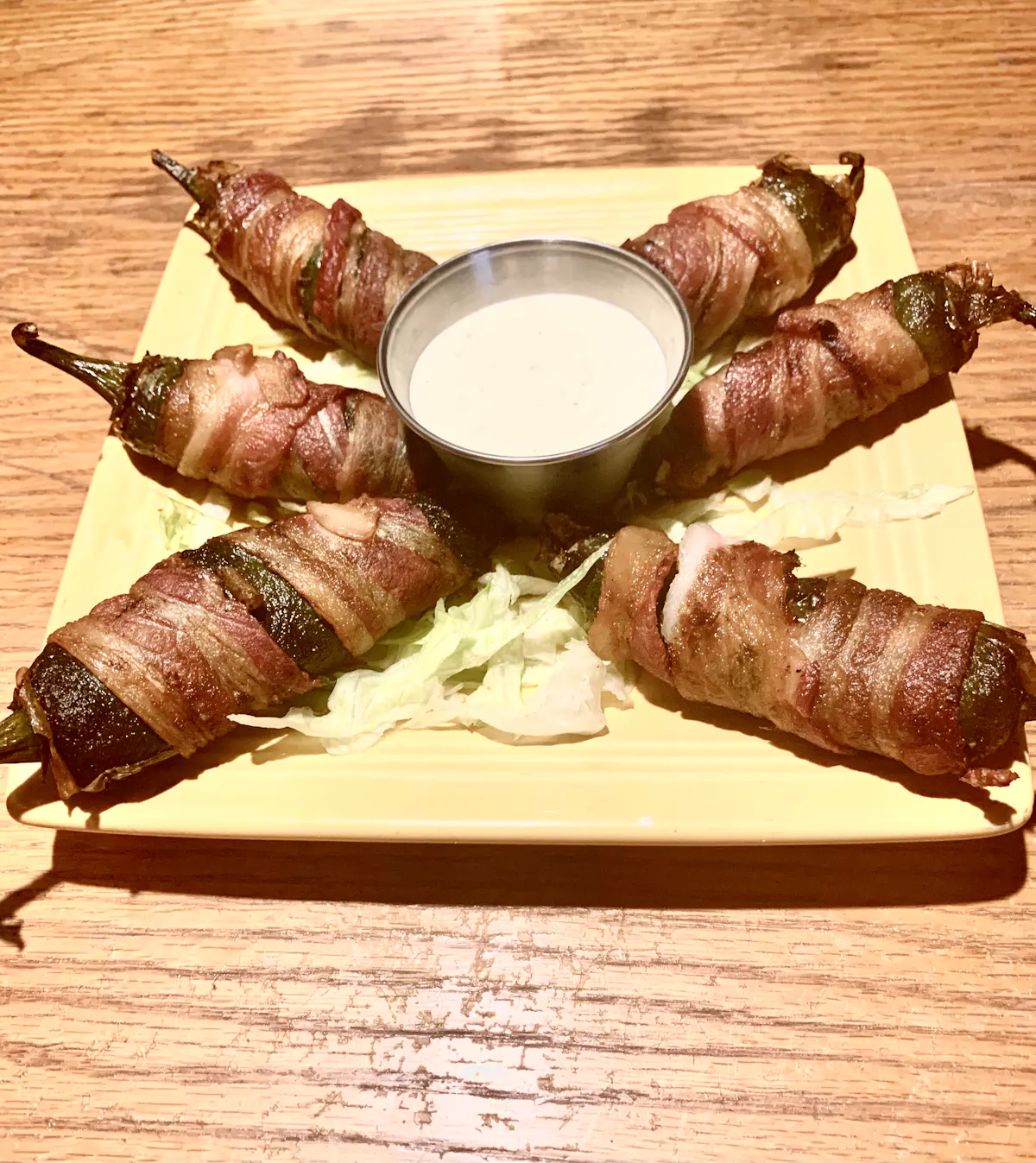 Jalapeños wrapped in bacon on top of wooden cutting board