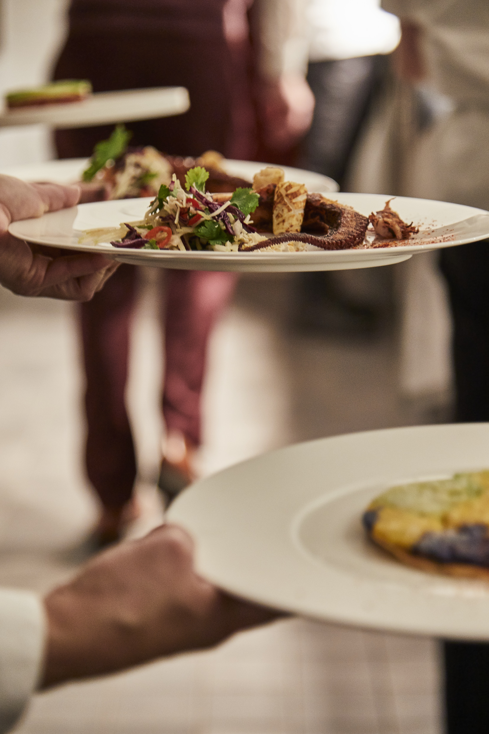 a person holding a plate of food on a table