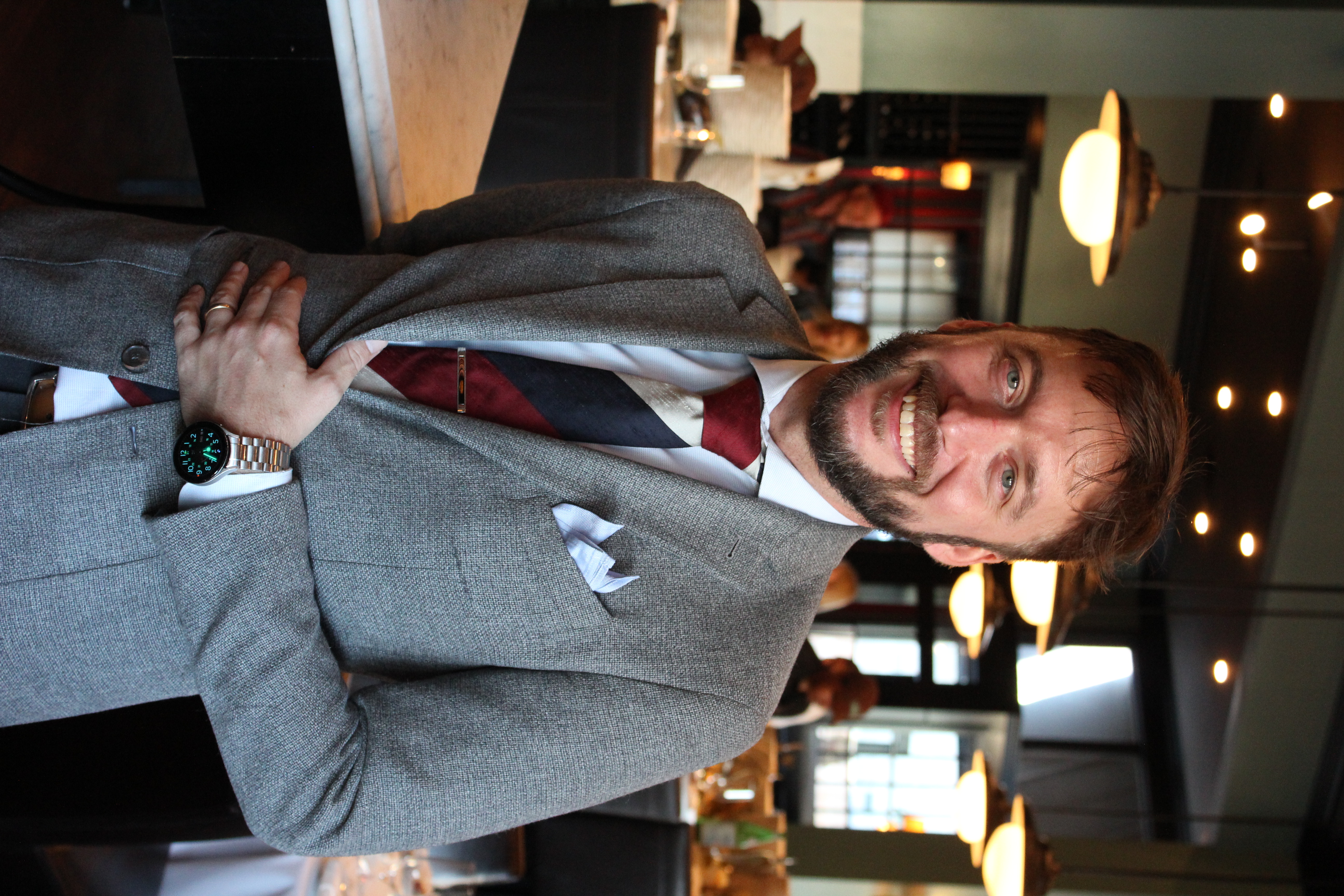 a man wearing a suit and tie smiling at the camera