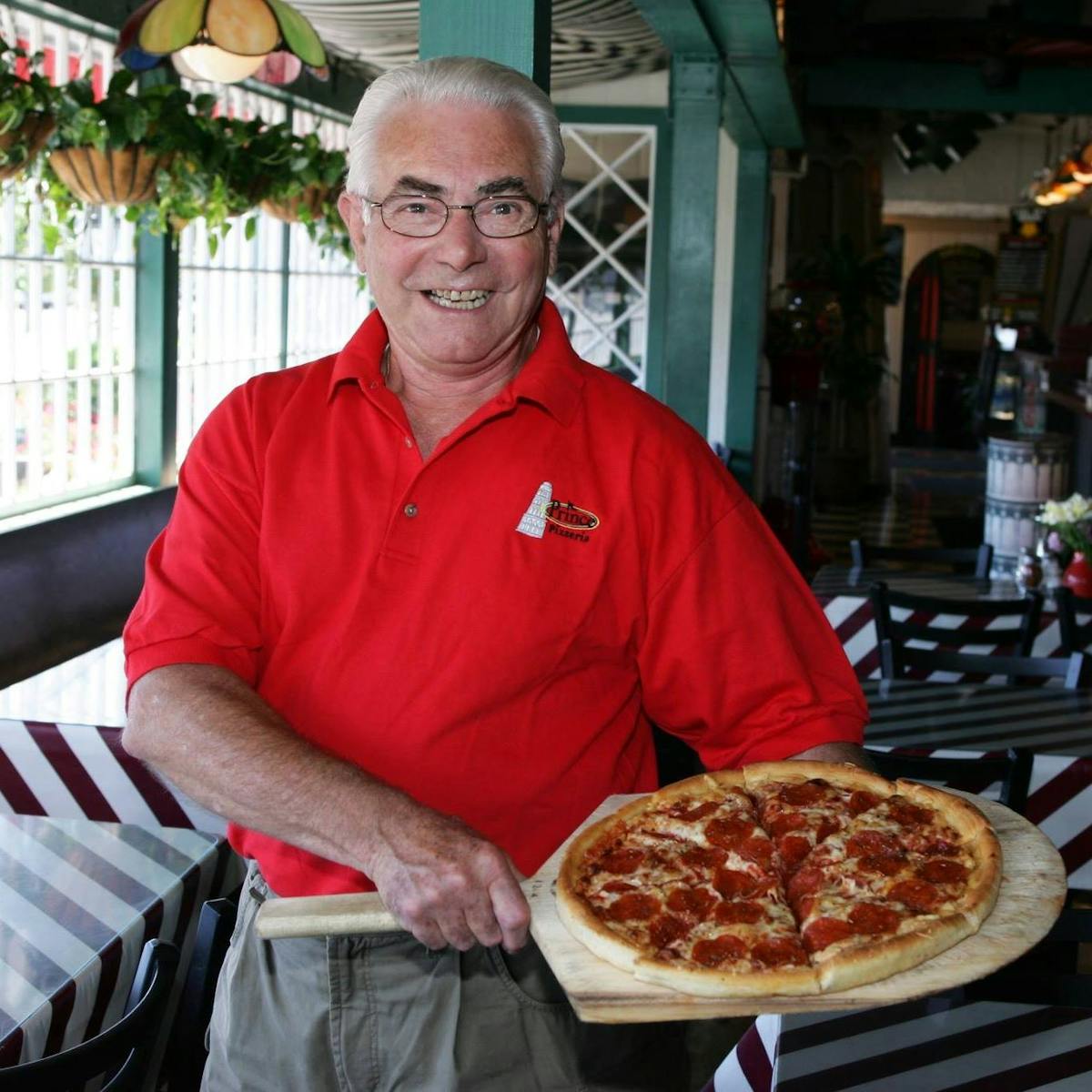 a man holding a pizza on a table