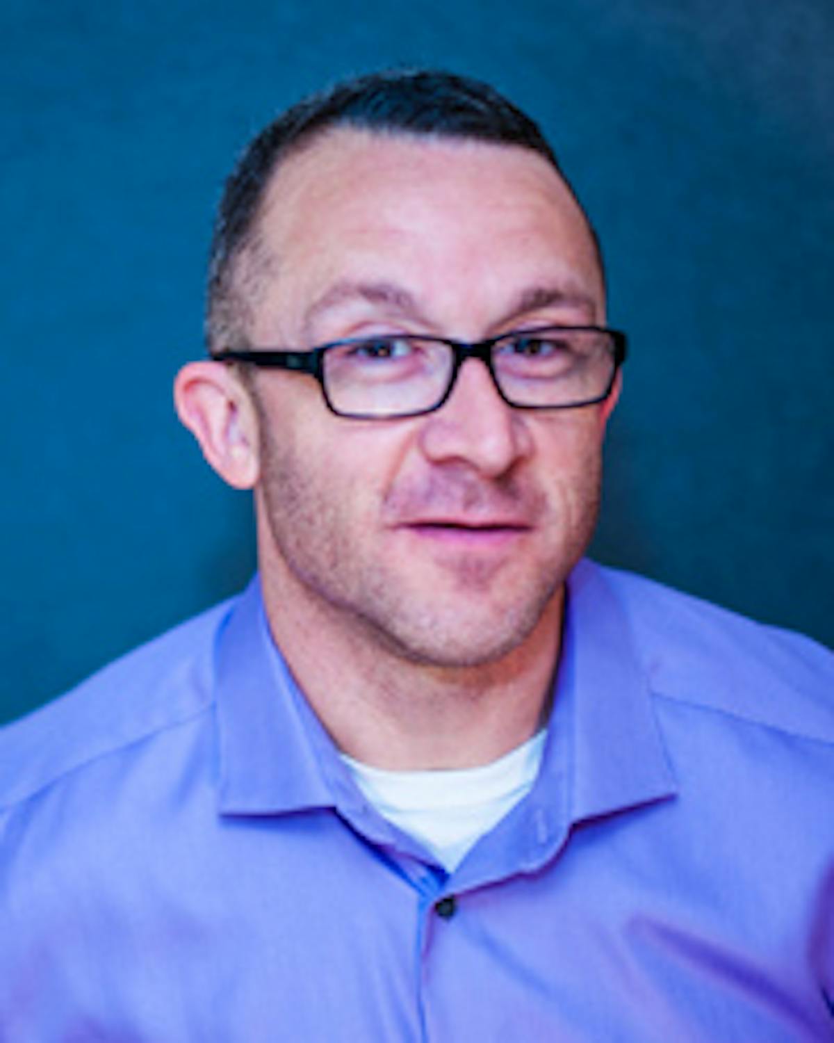 a man wearing glasses and smiling at the camera