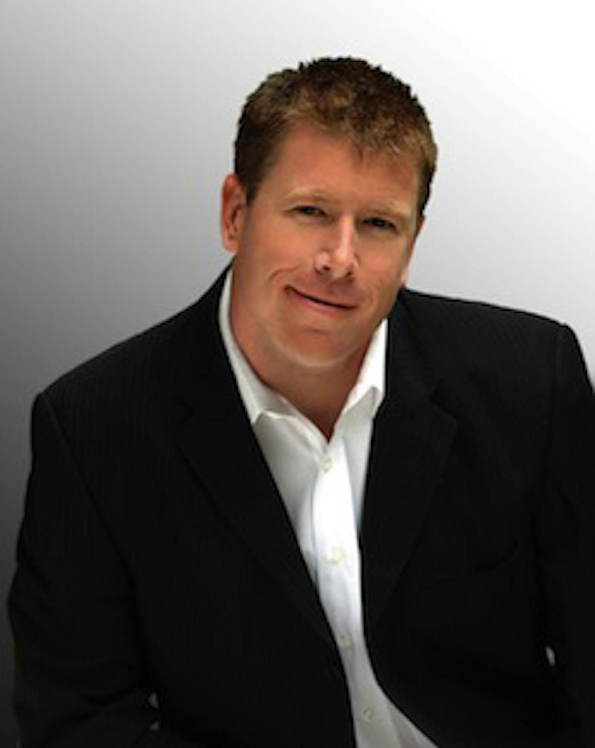 Jimmy Dunn wearing a suit and tie smiling at the camera