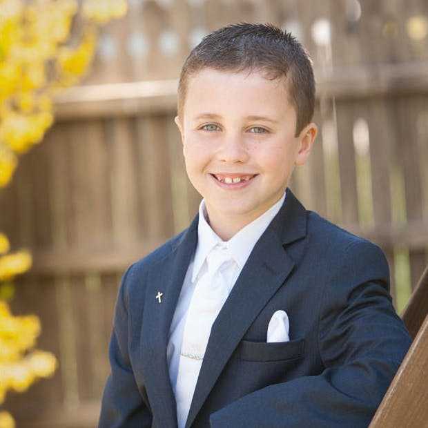 a young boy wearing a suit and tie smiling at the camera