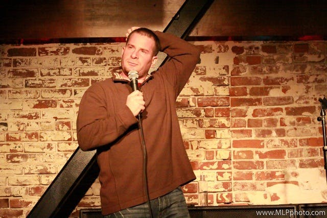 a man standing in front of a brick wall