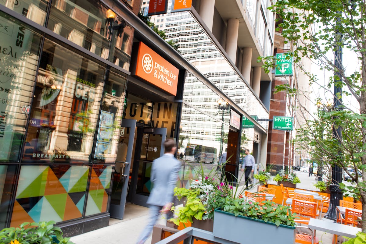 A man walks past the outside of a Protein Bar & Kitchen location