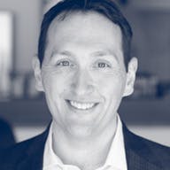 a man wearing a suit and tie smiling at the camera