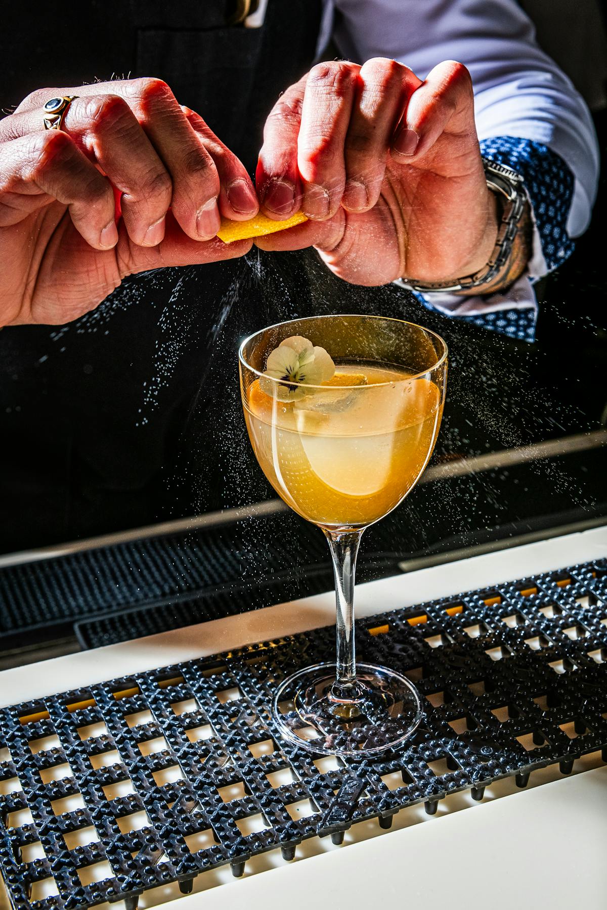 hand squeezing a citrus rind into a beautiful cocktail