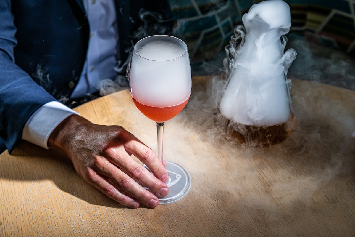a person holding a cocktail on a table