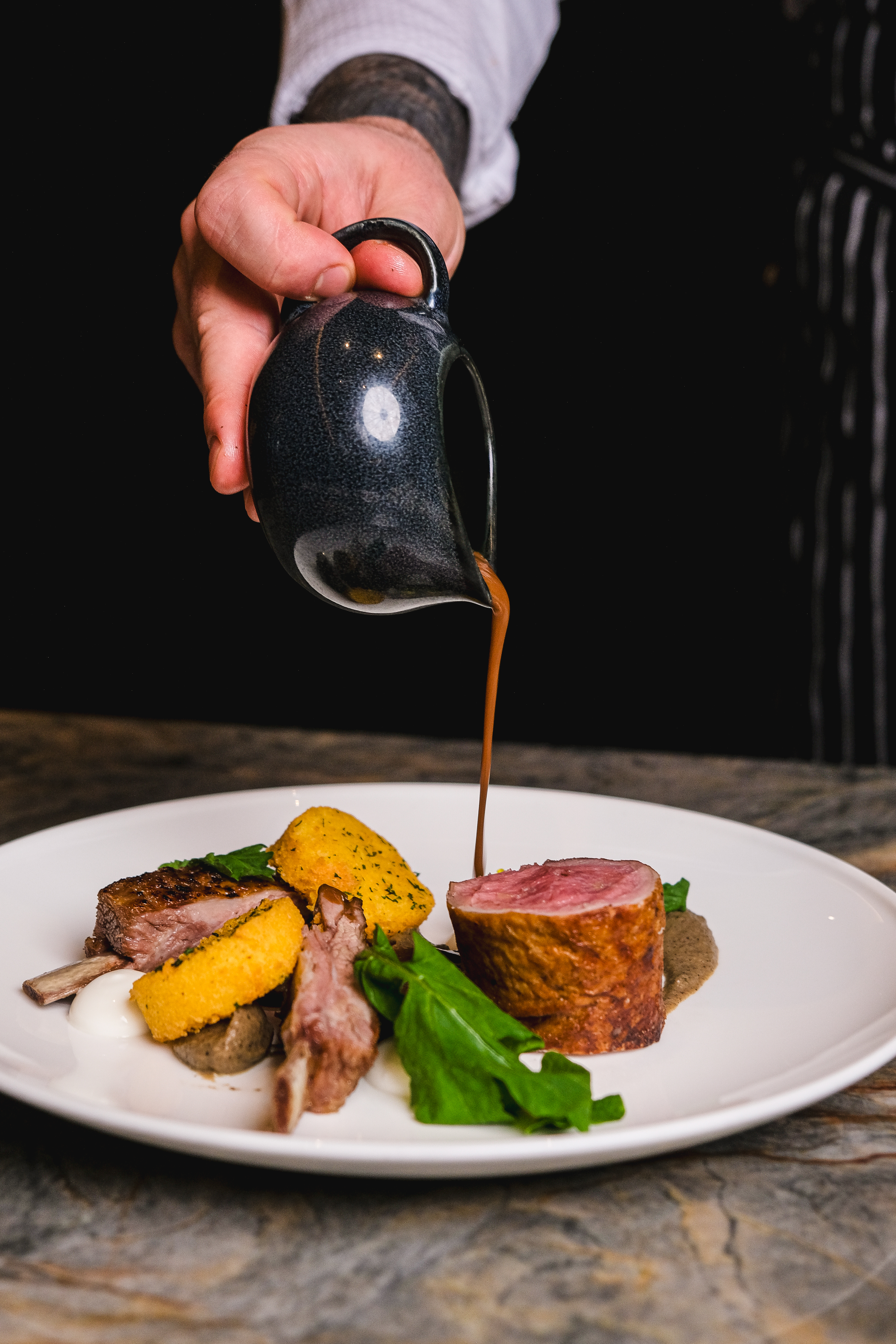 A chef elegantly pours sauce over a beautifully plated dish, enhancing its visual appeal and flavor