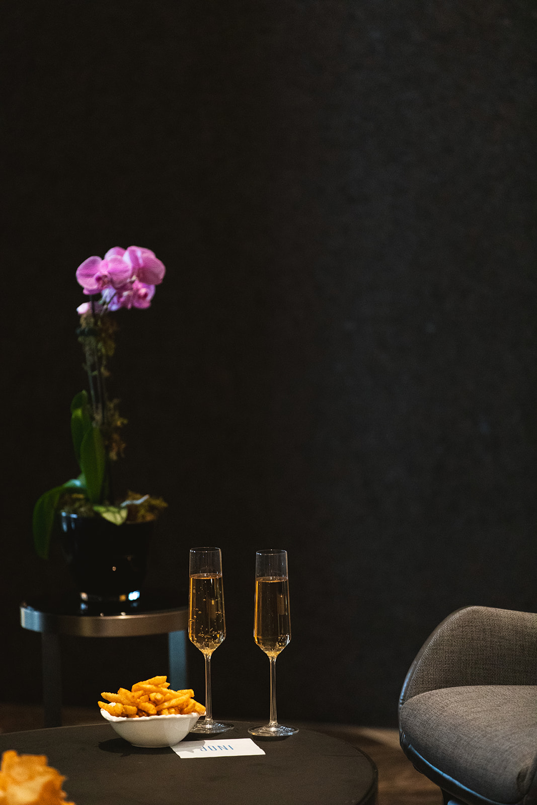 A room featuring a black wall and a single chair, creating a minimalist and modern aesthetic