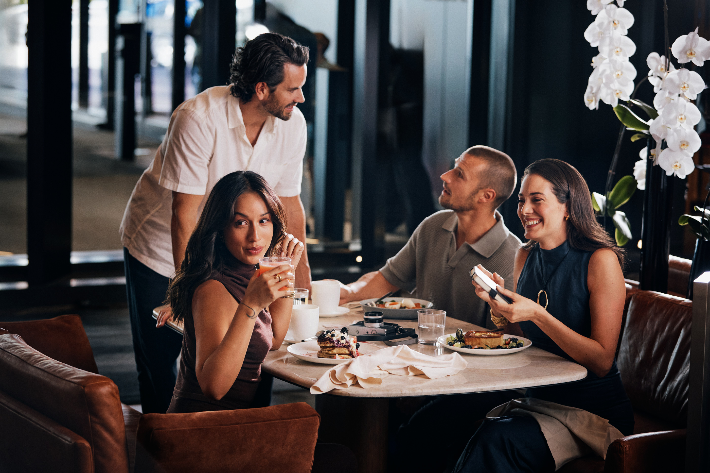 A diverse group of individuals gathered around a table, enjoying a meal together in a cozy restaurant setting