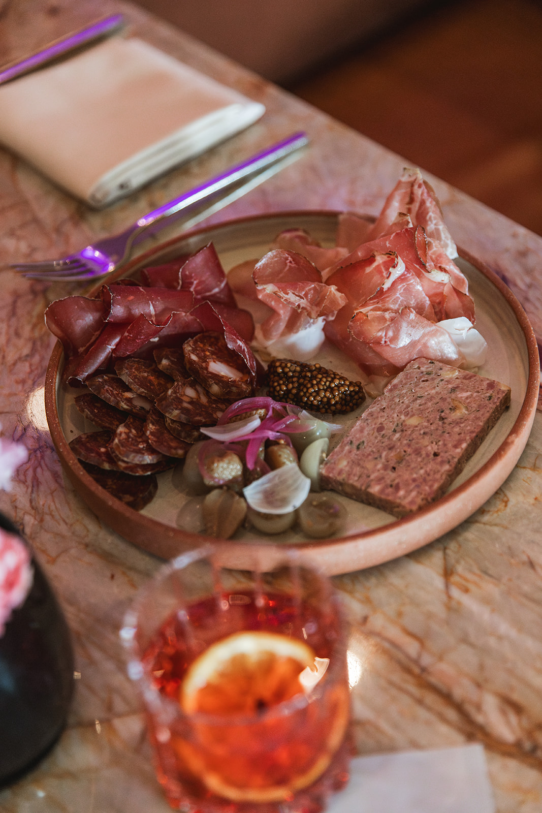 A table set with a glass of wine beside a plate of meat, creating an inviting dining atmosphere