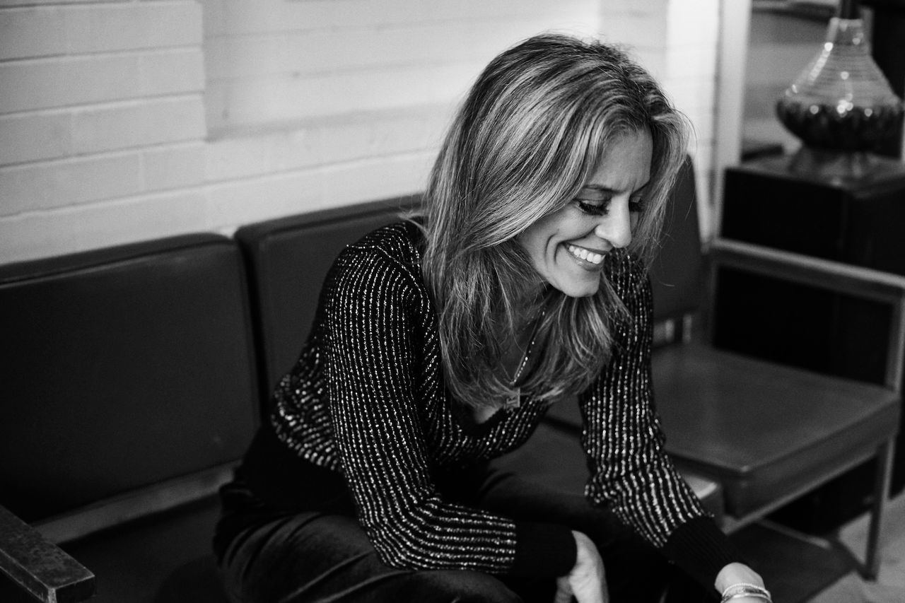 a woman smiling while sitting on a bench
