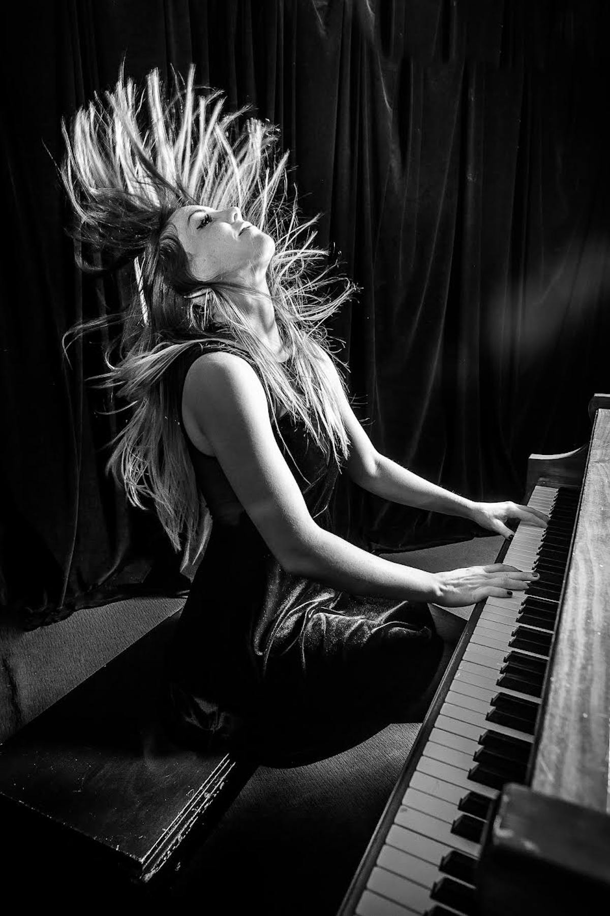 a girl sitting in front of a piano