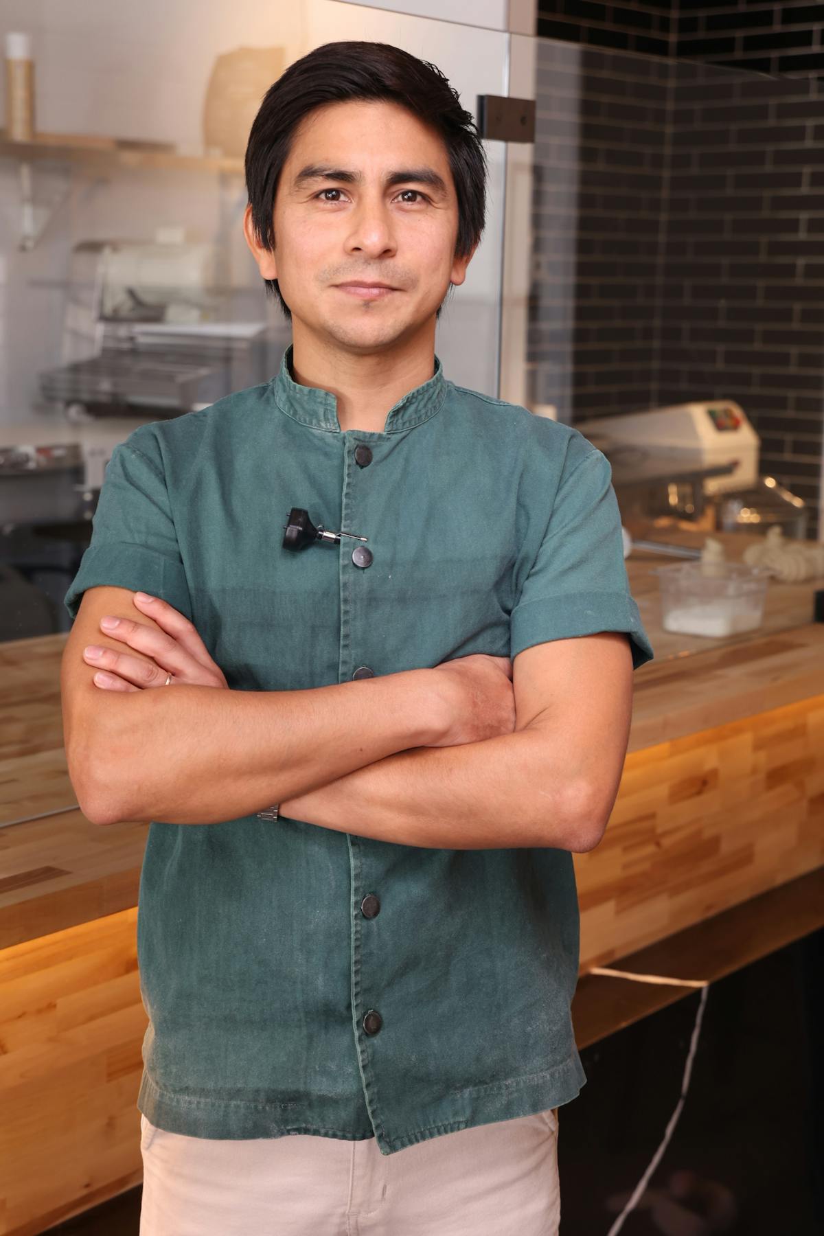a person wearing a green shirt is standing in the kitchen