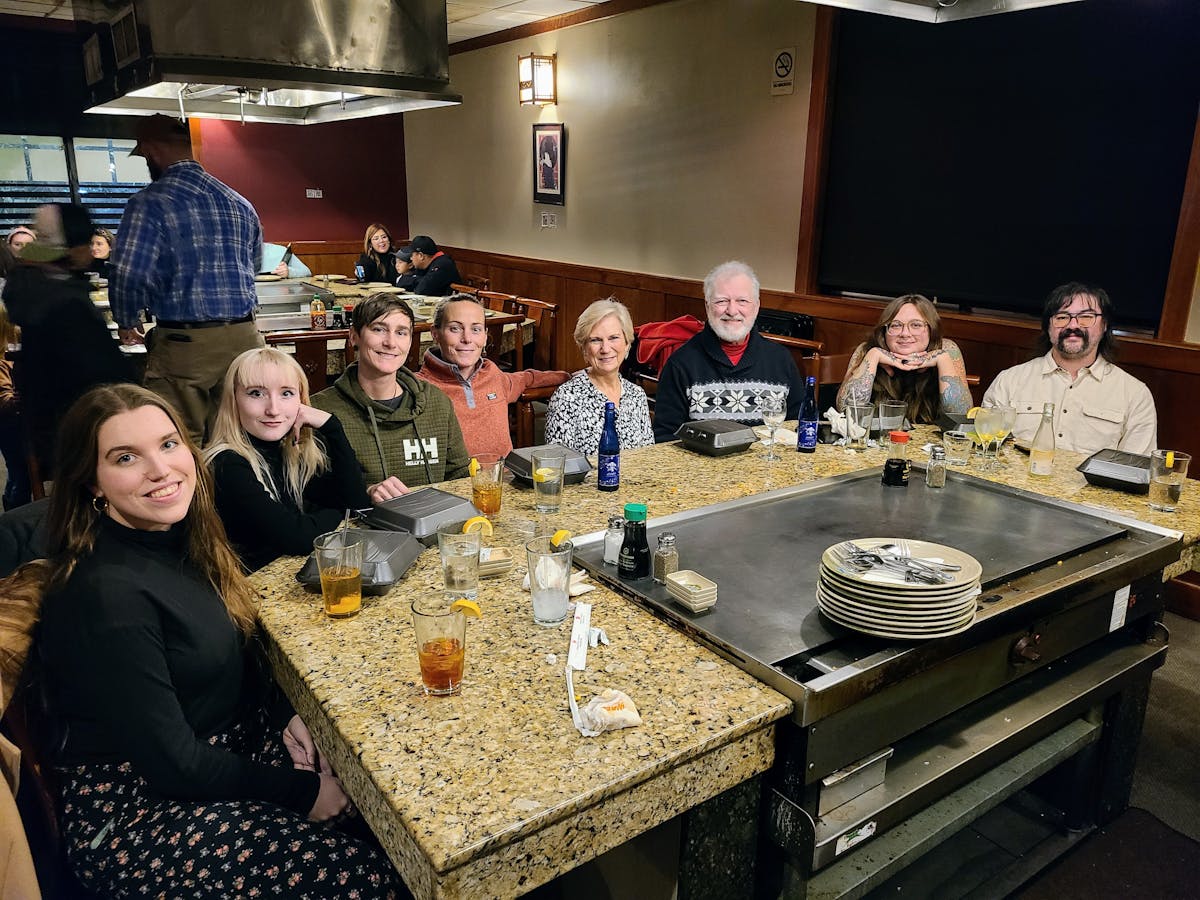 a group of people sitting at a table with a cake