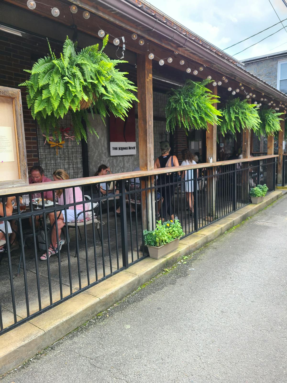 a group of people walking down a sidewalk next to a fence