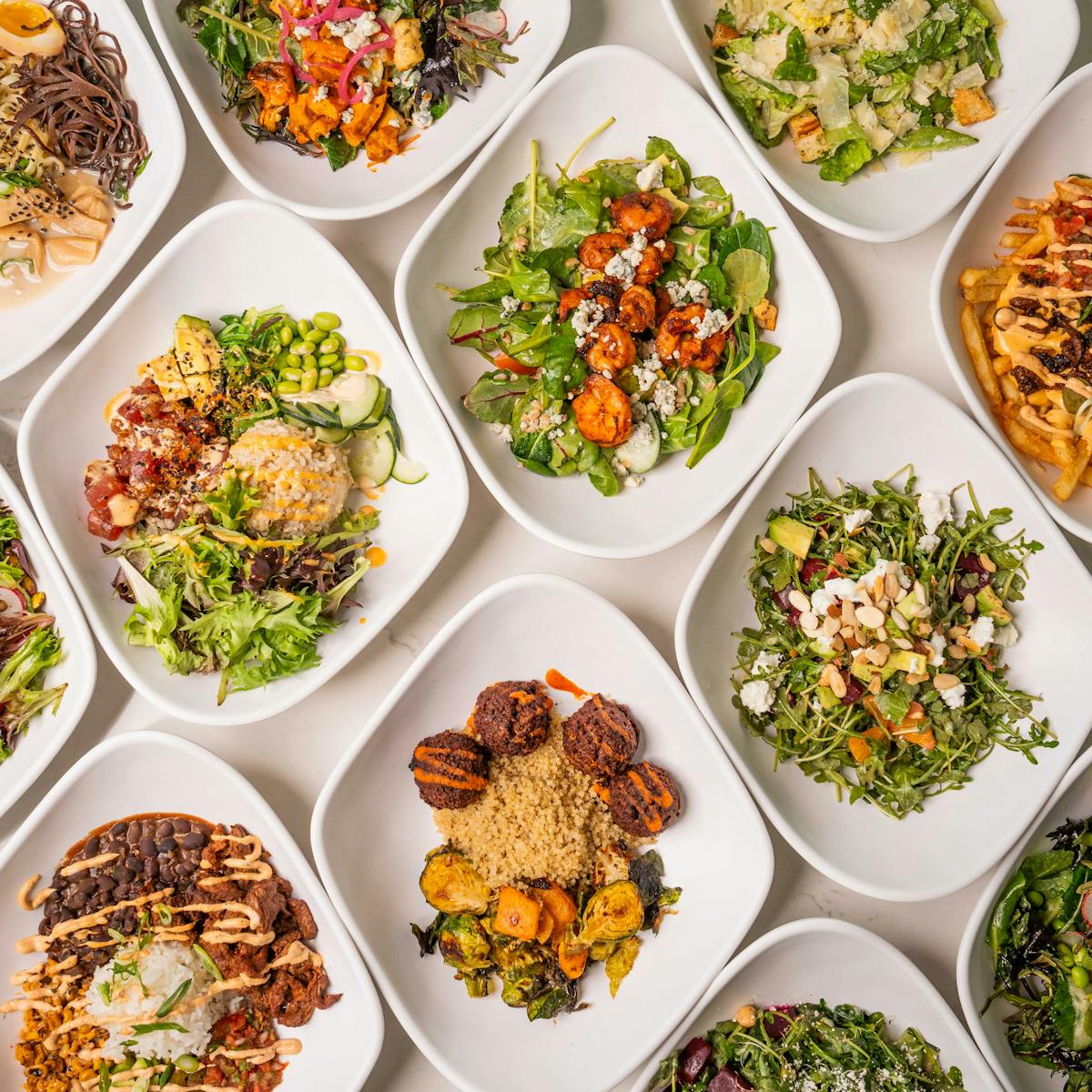 a bowl of pasta with many different types of food on a table
