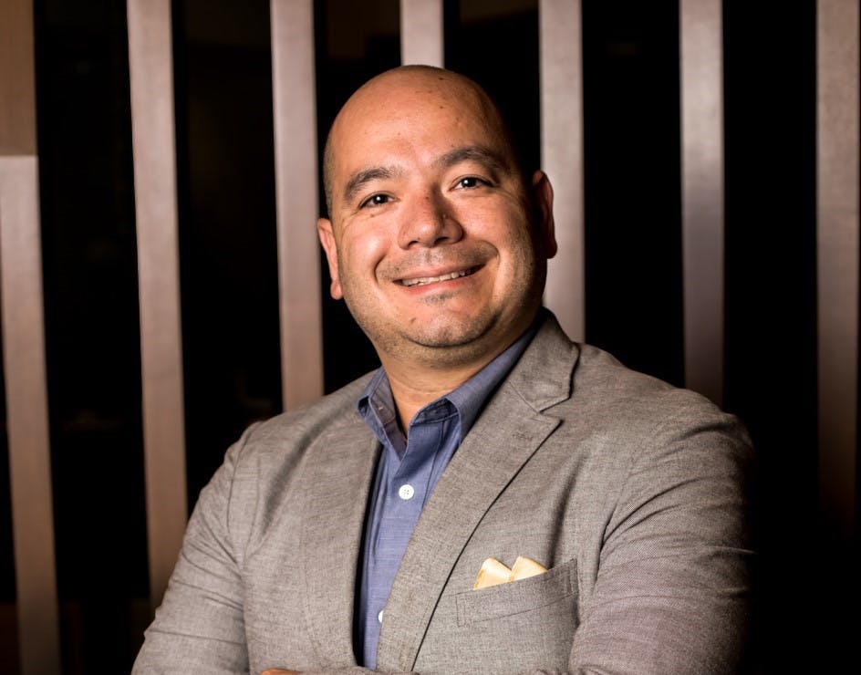 a man wearing a suit and tie smiling at the camera