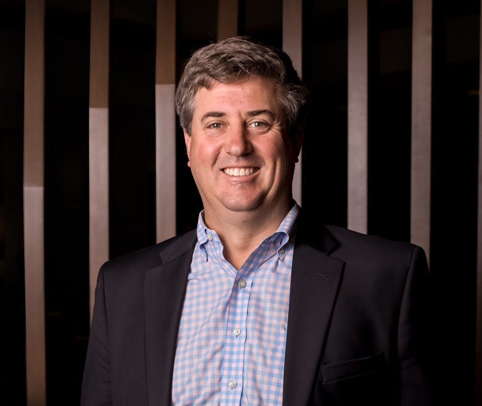 a man wearing a suit and tie smiling at the camera