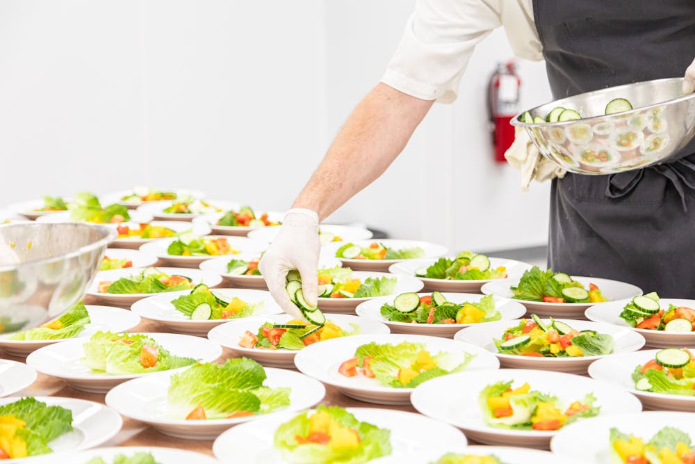 a person holding a plate of food on a table