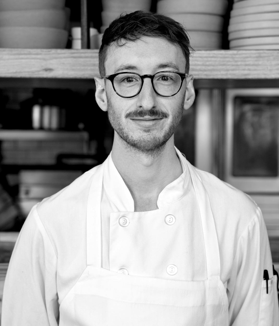 a man wearing glasses and smiling at the camera