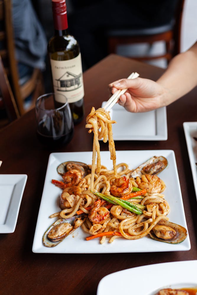 a person holding a plate of food on a table