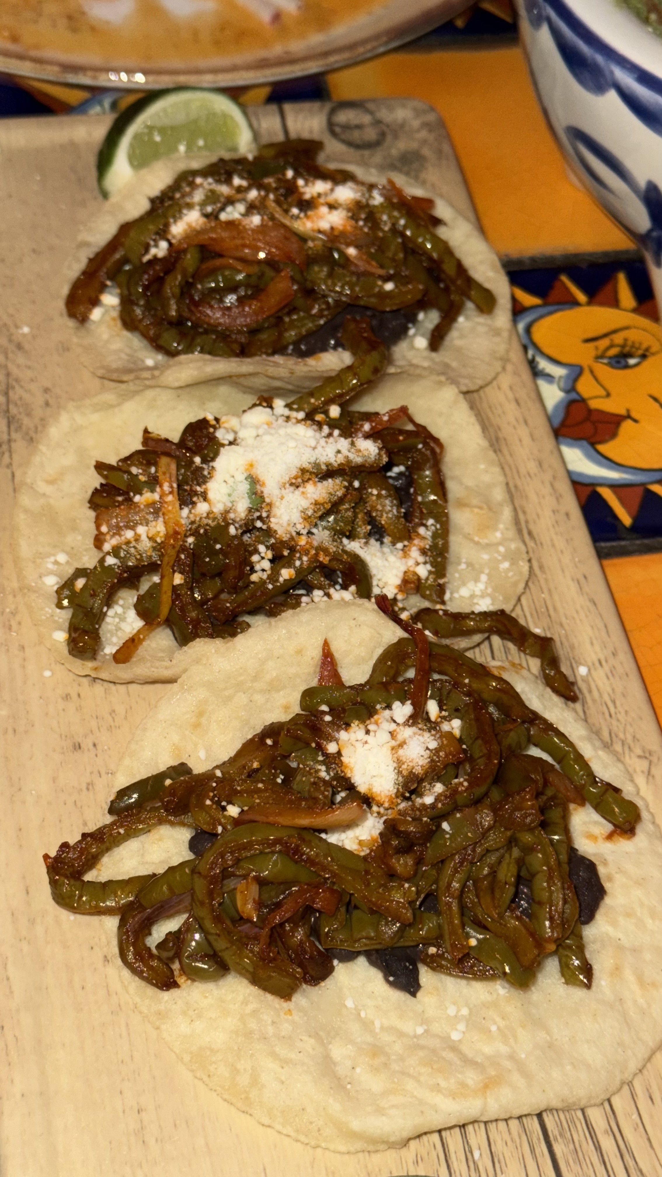 a group of tortillas with green beans and cheese on a wooden board