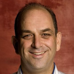 Brett Reichler wearing a suit and tie smiling at the camera