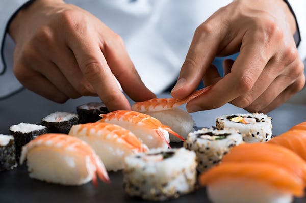 a close up of a person cutting a piece of sushi