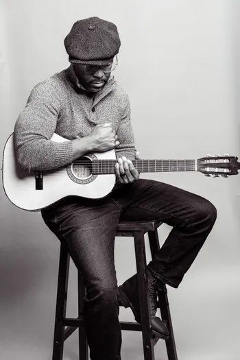 a man sitting on a stool playing a guitar