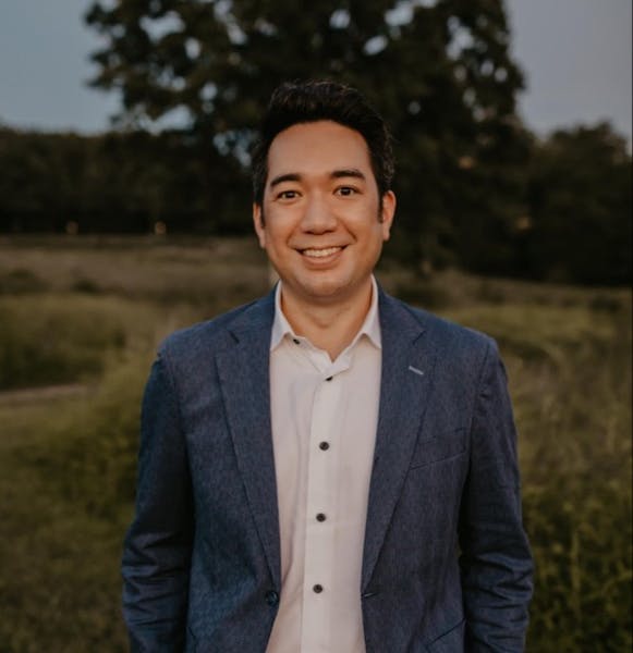 a man wearing a suit and tie smiling at the camera