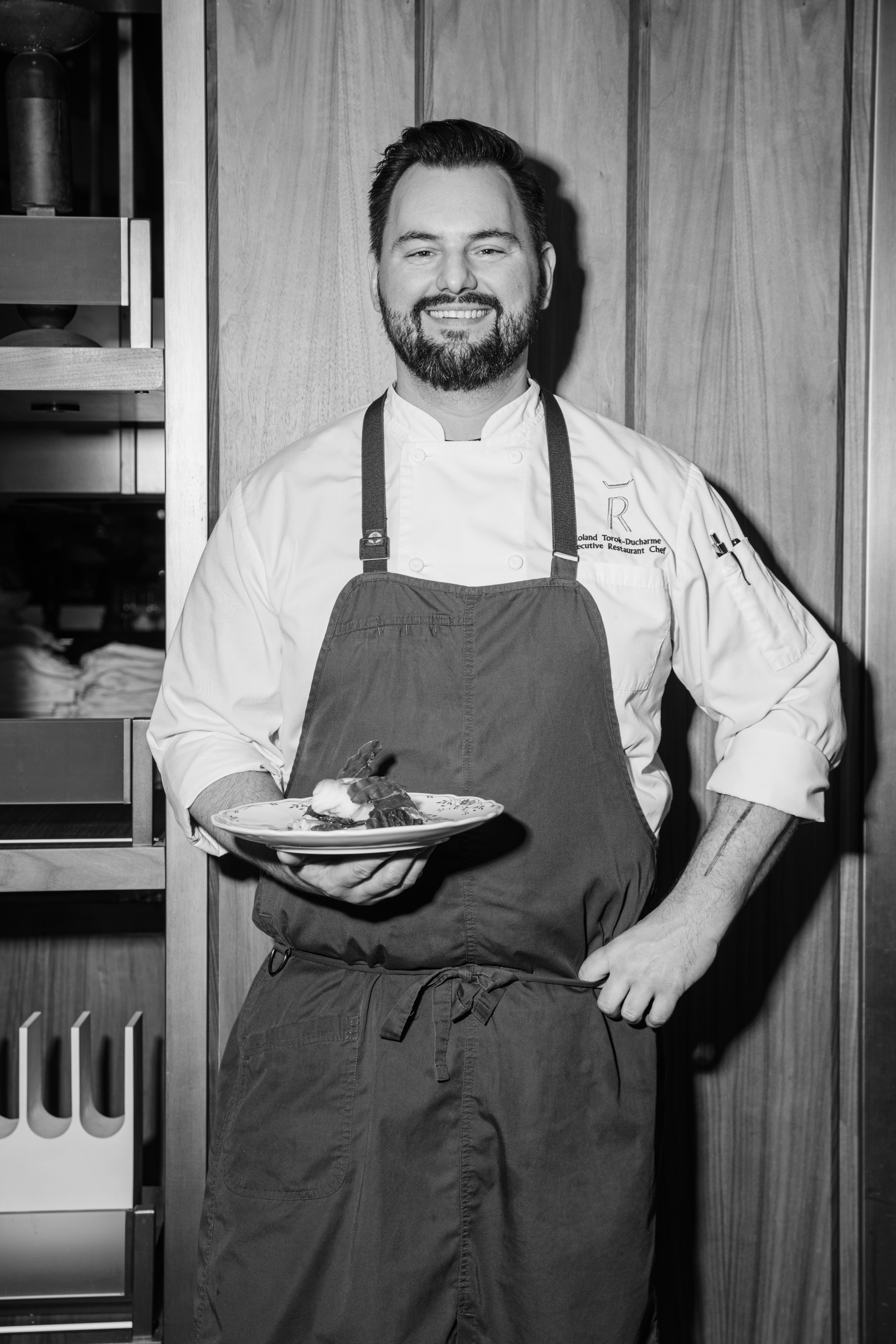 a man wearing an apron and holding a plate of food