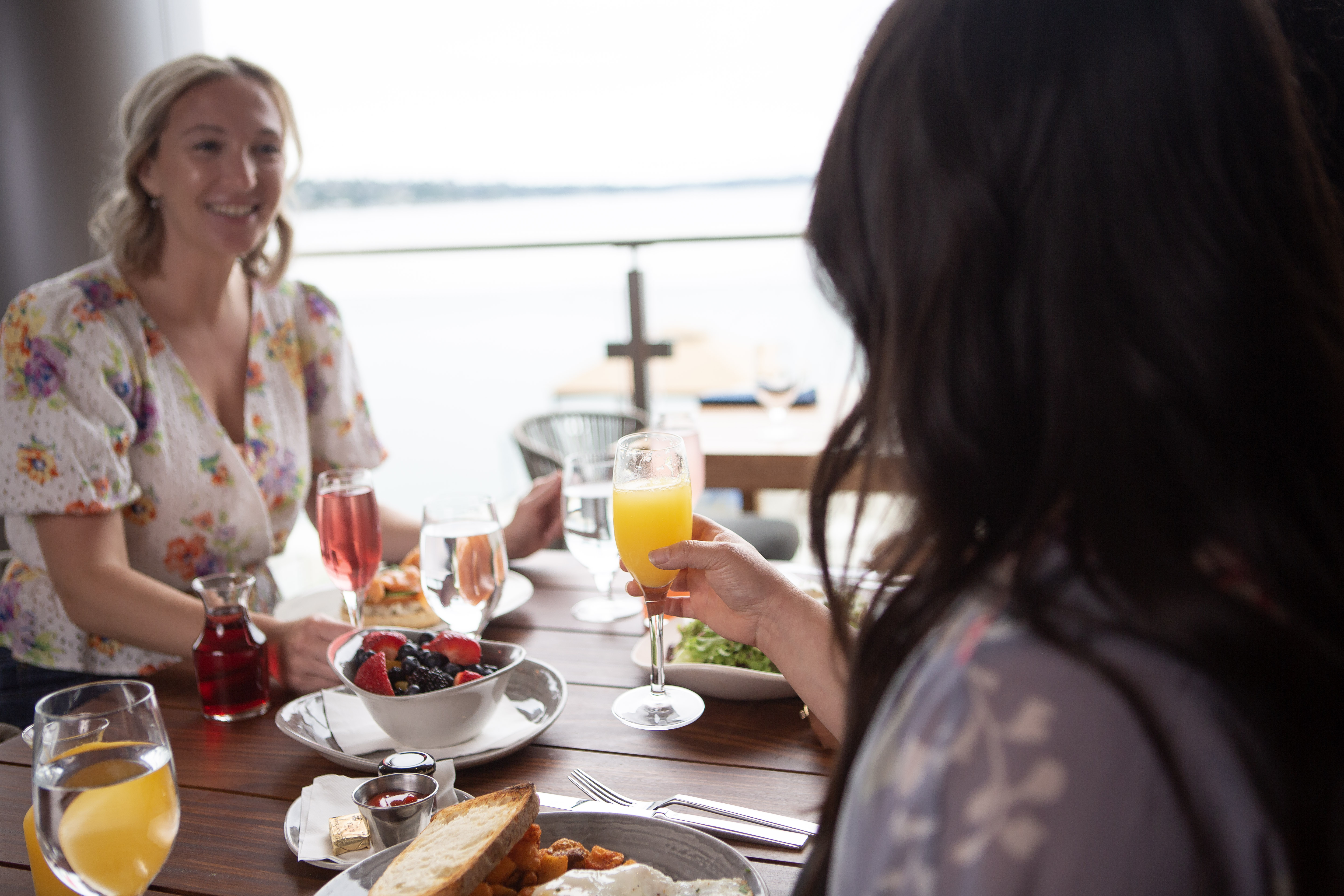 a group of women sitting at a table with food and drinks