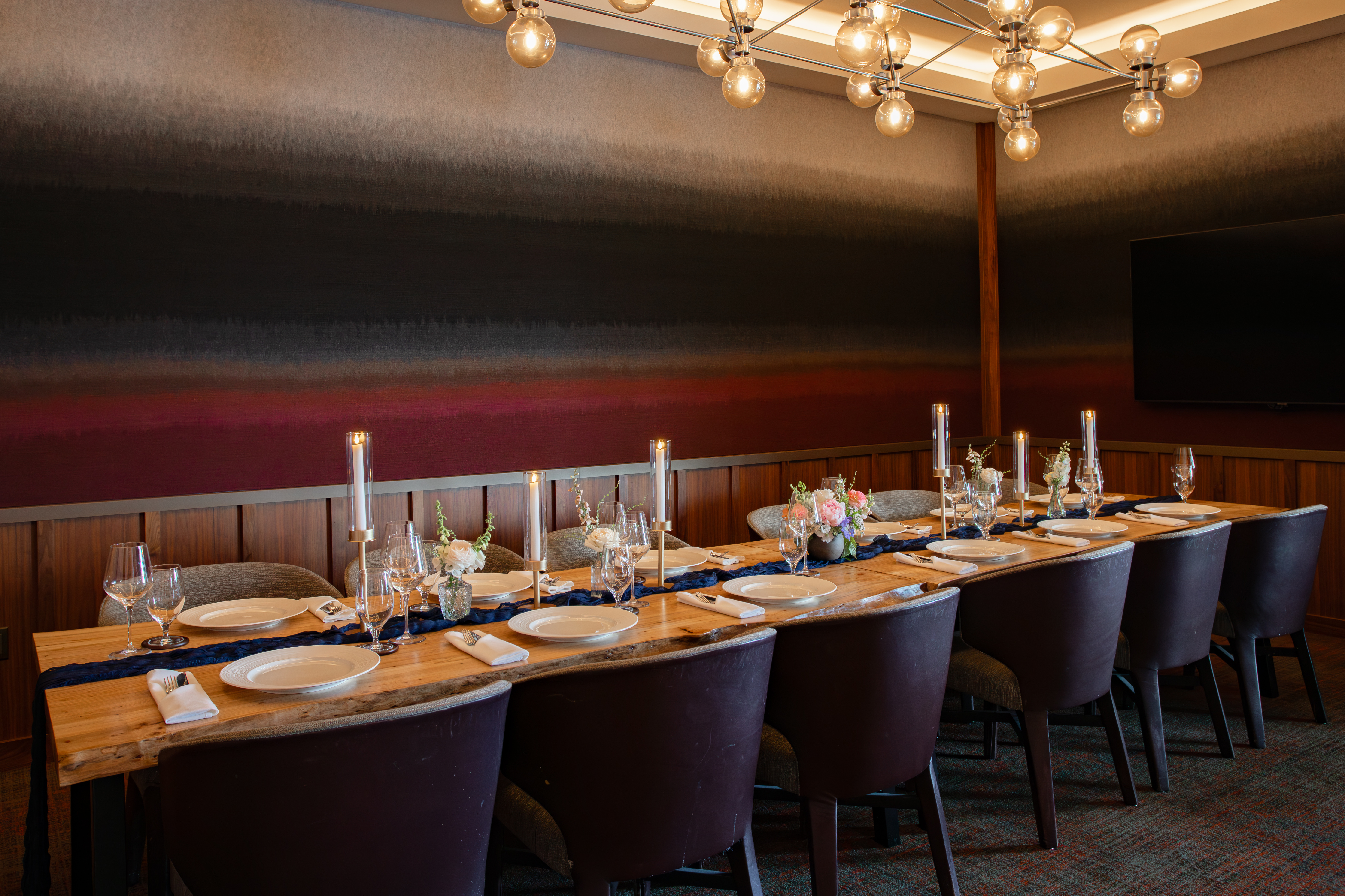 Long dining table with candles and flowers and table settings.