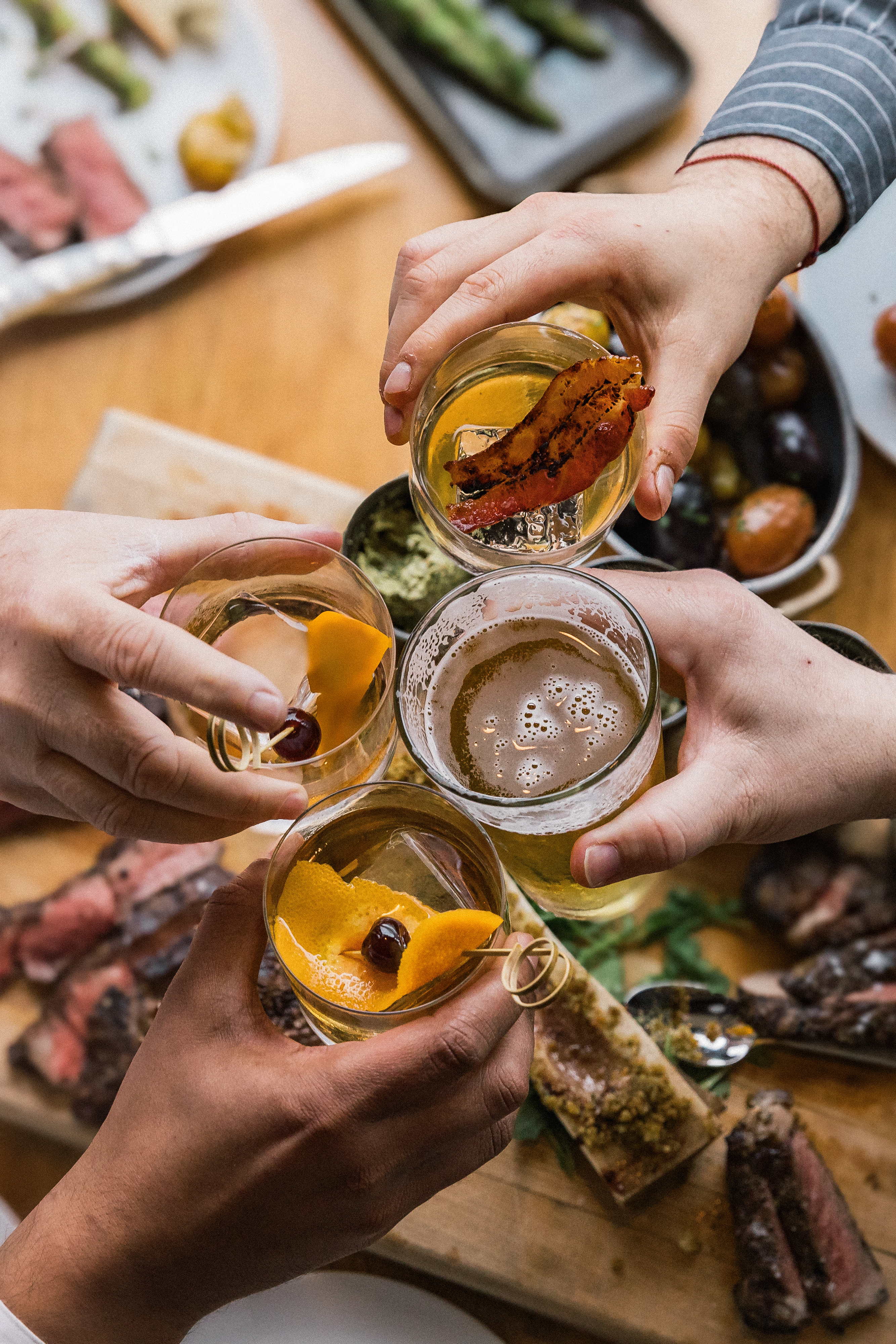 a group of hands holding glasses of drinks