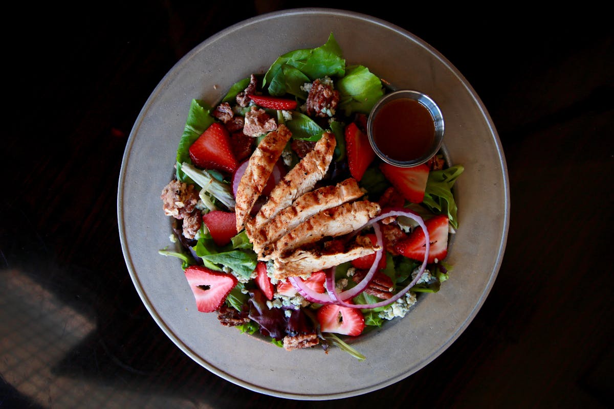 an overview of a plate filled with salad sided by a sauce