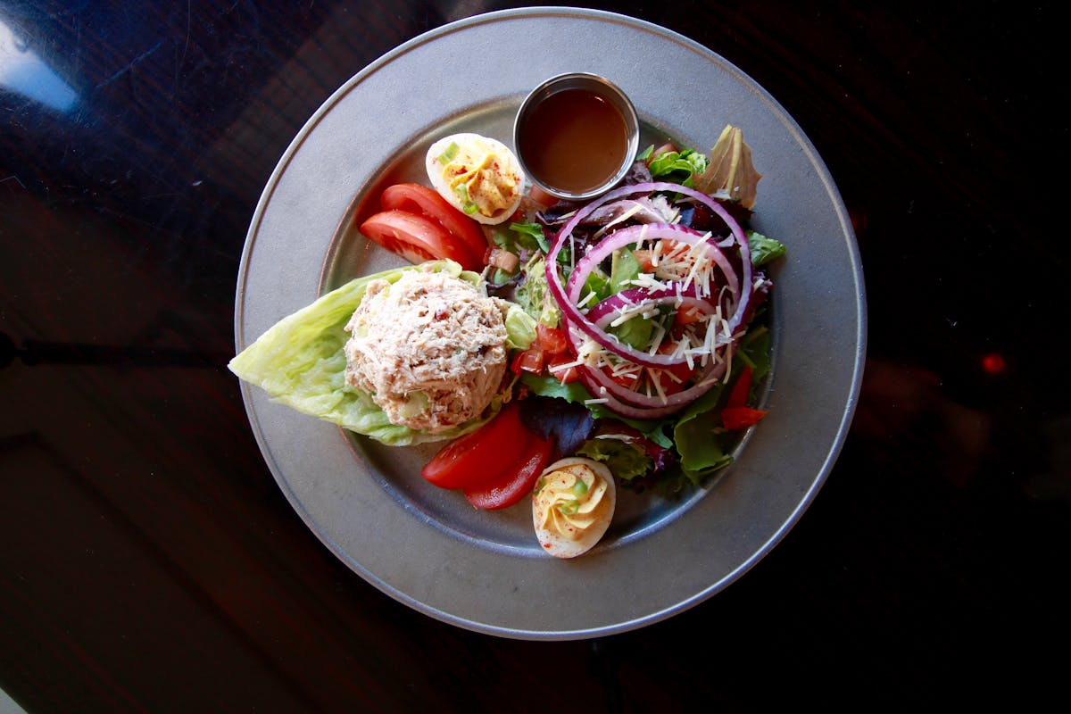 a plate filled with salad sided by a sauce