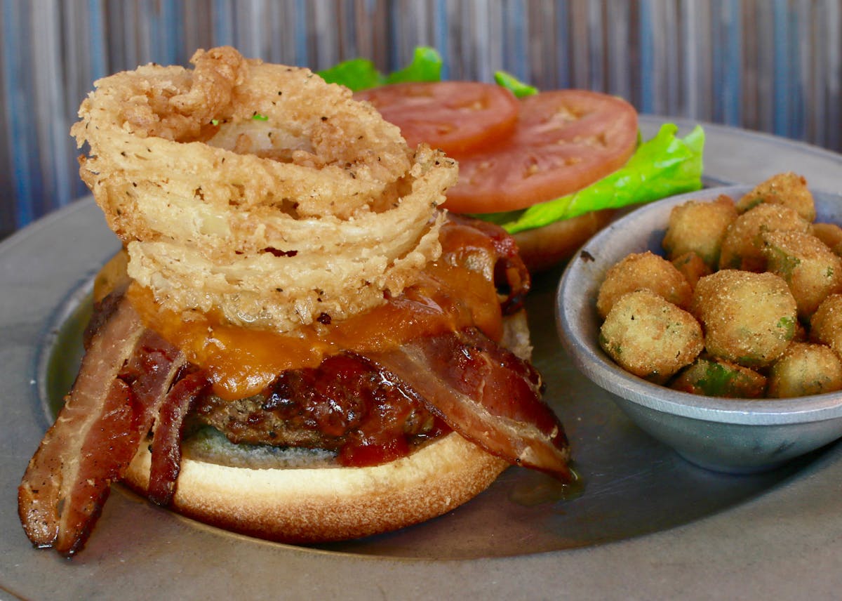 a close up of a sandwich sided by a salad and hash browns