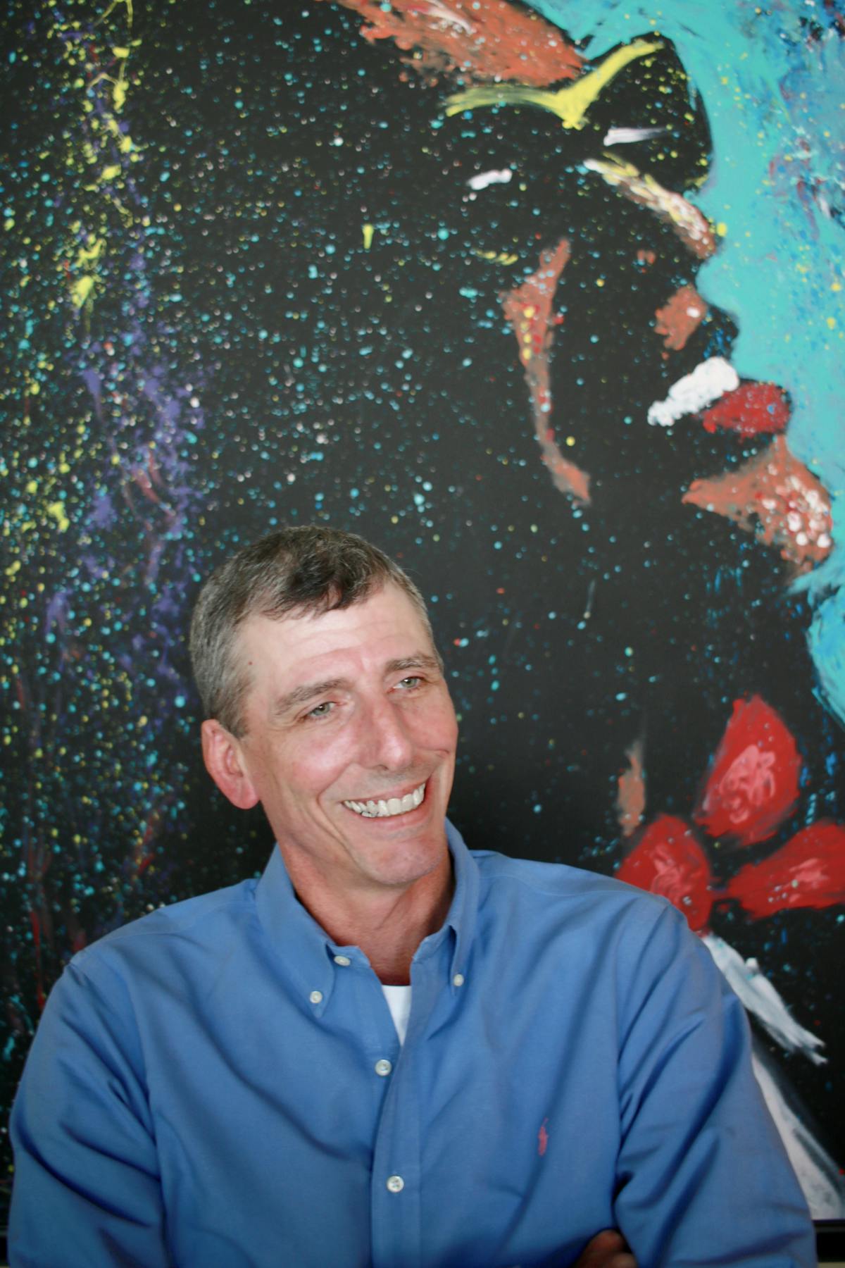 a man in a blue shirt smiling for the camera